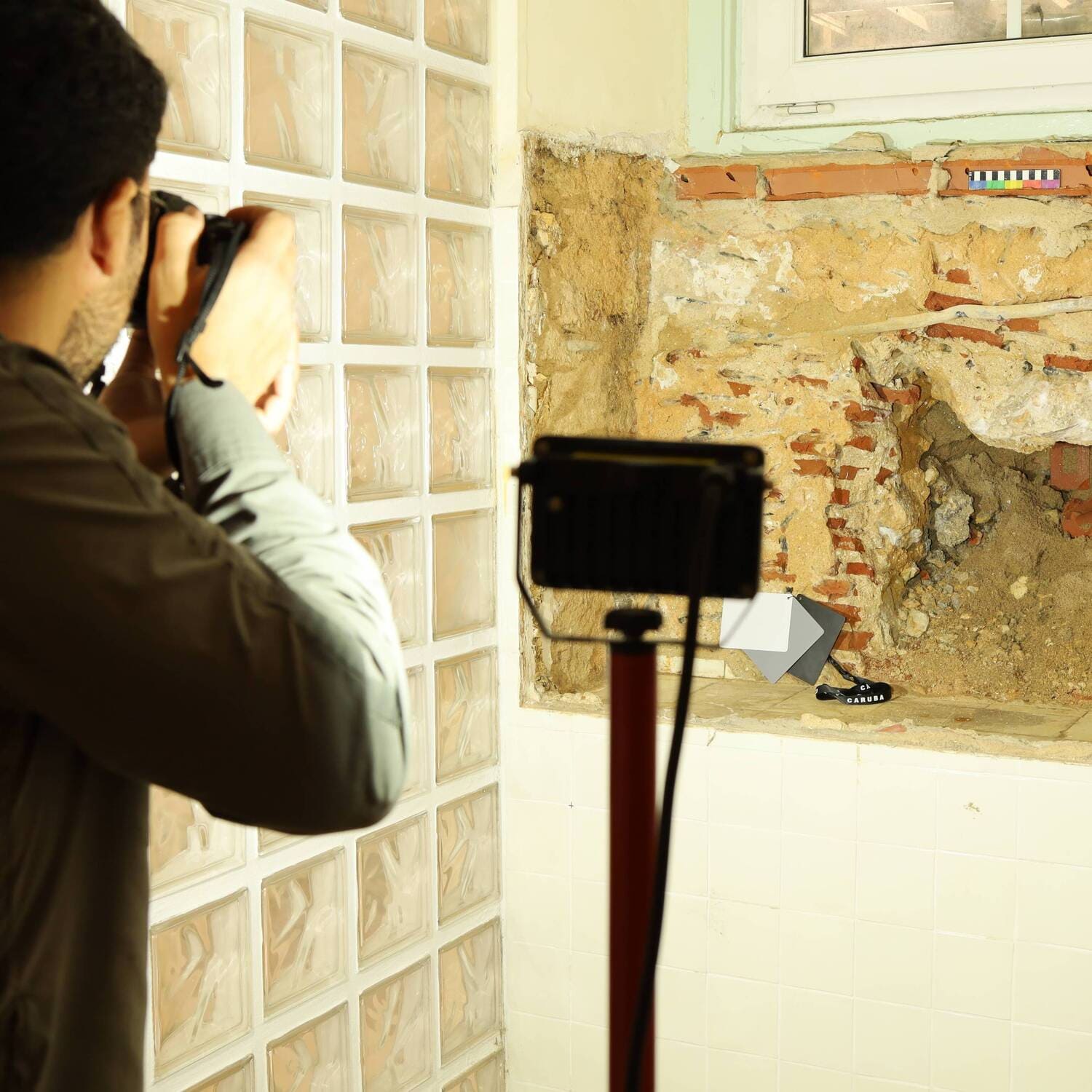 Investigador utiliza equipamento de fotografia profissiona para documentar com precisão uma estrutura arqueológica urbana.